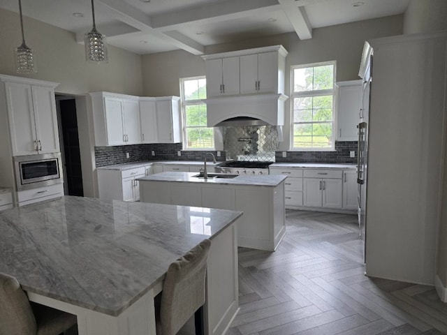 128 Gloria Blvd, Smithville, TX 78957 - kitchen featuring a center island with sink, stainless steel microwave, premium range hood, tasteful backsplash, and coffered ceiling