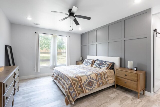 116 Mallard Rd, Bastrop, TX 78602 - bedroom featuring light wood finished floors, a decorative wall, recessed lighting, a barn door, and baseboards