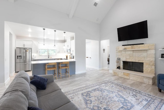 116 Mallard Rd, Bastrop, TX 78602 - living area featuring light wood-type flooring, high vaulted ceiling, baseboards, a fireplace, and beamed ceiling