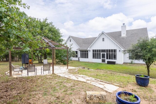 116 Mallard Rd, Bastrop, TX 78602 - back of house featuring board and batten siding, a chimney, roof with shingles, a patio area, and a lawn