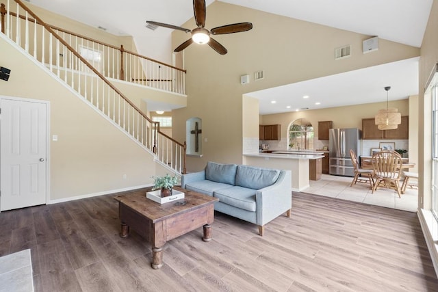 17704 Miller Falls Cv, Round Rock, TX 78681 - living room with high vaulted ceiling, stairway, light wood finished floors, a ceiling fan, and arched walkways