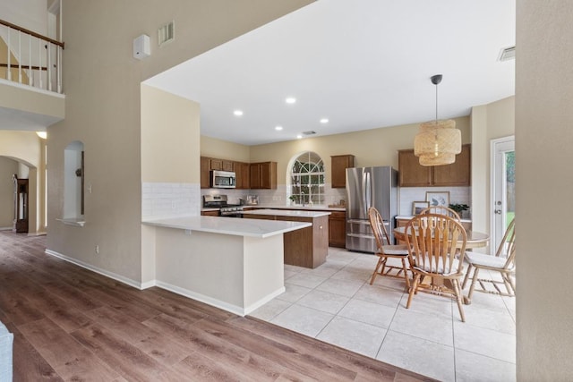 17704 Miller Falls Cv, Round Rock, TX 78681 - kitchen featuring stainless steel appliances, arched walkways, light countertops, brown cabinets, and backsplash