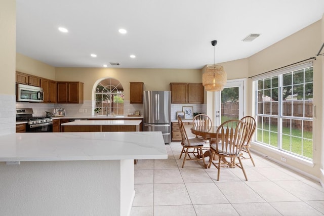 17704 Miller Falls Cv, Round Rock, TX 78681 - kitchen featuring stainless steel appliances, brown cabinets, healthy amount of natural light, and recessed lighting