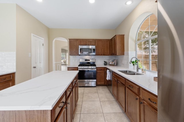 17704 Miller Falls Cv, Round Rock, TX 78681 - kitchen featuring appliances with stainless steel finishes, decorative backsplash, arched walkways, a center island, and light stone counters