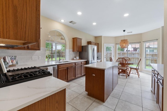 17704 Miller Falls Cv, Round Rock, TX 78681 - kitchen with freestanding refrigerator, a center island, backsplash, brown cabinetry, and recessed lighting