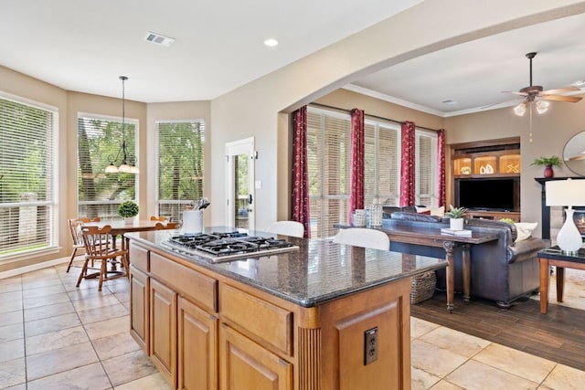 1613 Westend Pl, Round Rock, TX 78681 - kitchen with stainless steel gas cooktop, ceiling fan, a center island, dark stone counters, and light tile patterned floors