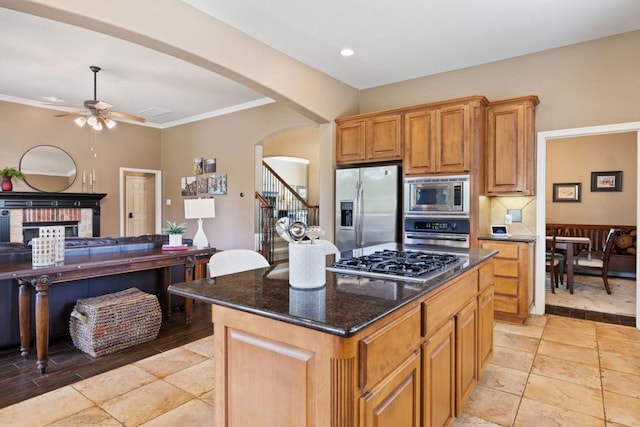 1613 Westend Pl, Round Rock, TX 78681 - kitchen with stainless steel appliances, arched walkways, a ceiling fan, dark stone counters, and a center island