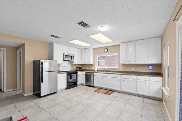 2507 Byfield Dr, Cedar Park, TX 78613 - kitchen featuring appliances with stainless steel finishes, a textured ceiling, white cabinetry, dark countertops, and light tile patterned flooring
