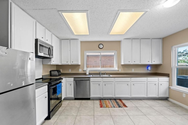 2507 Byfield Dr, Cedar Park, TX 78613 - kitchen featuring appliances with stainless steel finishes, white cabinetry, a textured ceiling, dark countertops, and light tile patterned flooring