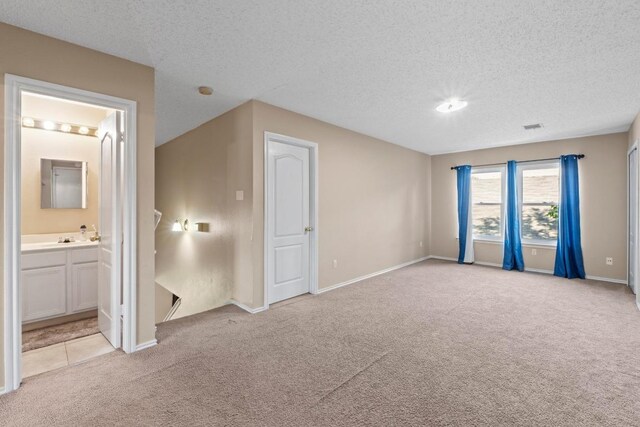 2507 Byfield Dr, Cedar Park, TX 78613 - unfurnished bedroom featuring light colored carpet, a textured ceiling, and ensuite bath