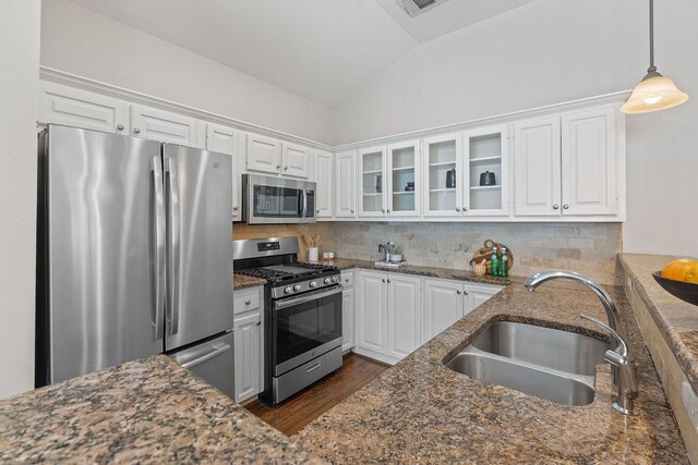 6706 Fort Davis Cv Unit B, Austin, TX 78731 - kitchen featuring stainless steel appliances, white cabinetry, glass insert cabinets, vaulted ceiling, and dark stone countertops