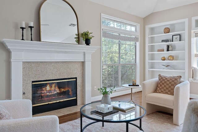 6706 Fort Davis Cv Unit B, Austin, TX 78731 - living room featuring built in shelves, lofted ceiling, a tiled fireplace, and wood finished floors