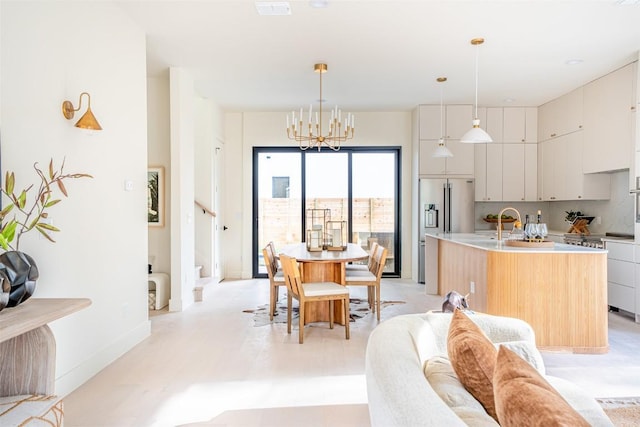 2301 Canterbury, Austin, TX 78702 - kitchen with stainless steel fridge with ice dispenser, a chandelier, modern cabinets, a center island with sink, and light countertops