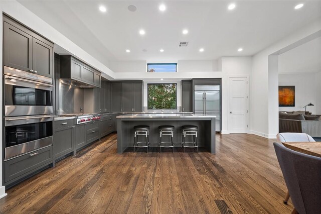 9517 Veletta Pl, Austin, TX 78735 - kitchen featuring open floor plan, a kitchen island, appliances with stainless steel finishes, dark wood-type flooring, and a breakfast bar area