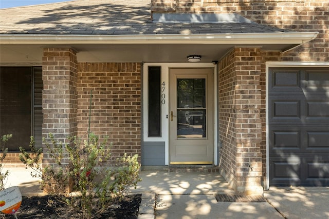 4700 Fallenash Dr, Austin, TX 78725 - view of exterior entry featuring a shingled roof, brick siding, and an attached garage