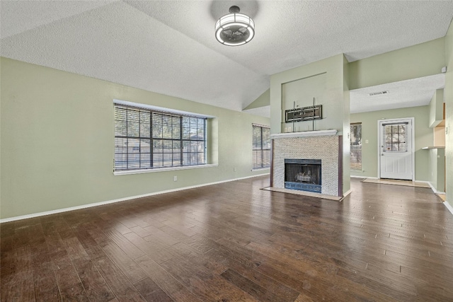 4700 Fallenash Dr, Austin, TX 78725 - unfurnished living room with wood finished floors, healthy amount of natural light, a fireplace with flush hearth, a textured ceiling, and vaulted ceiling
