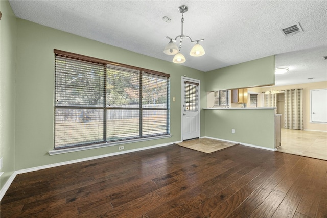4700 Fallenash Dr, Austin, TX 78725 - spare room with a chandelier, hardwood / wood-style flooring, a textured ceiling, and baseboards