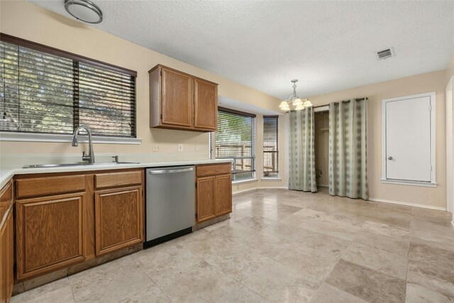 4700 Fallenash Dr, Austin, TX 78725 - kitchen with stainless steel dishwasher, a sink, a chandelier, brown cabinets, and a textured ceiling