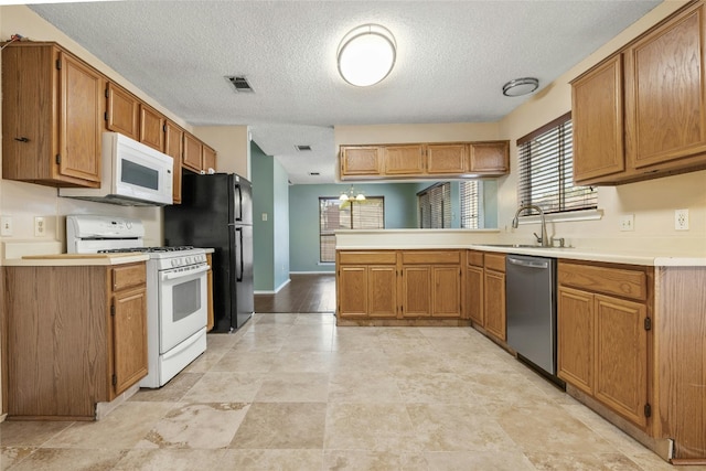 4700 Fallenash Dr, Austin, TX 78725 - kitchen featuring white appliances, a peninsula, a sink, a textured ceiling, and light countertops