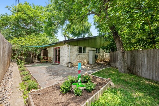3102 Glen Ora St Unit 102, Austin, TX 78704 - rear view of house featuring stone siding, a fenced backyard, and a patio