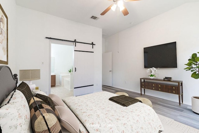 1310 Rainbow Parke Dr, Round Rock, TX 78665 - bedroom with a barn door, wood finished floors, ensuite bathroom, and a ceiling fan