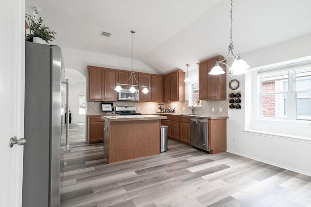 1310 Rainbow Parke Dr, Round Rock, TX 78665 - kitchen featuring appliances with stainless steel finishes, light wood finished floors, vaulted ceiling, a center island, and tasteful backsplash