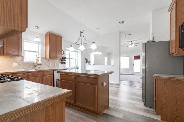 1310 Rainbow Parke Dr, Round Rock, TX 78665 - kitchen with light wood-style floors, a kitchen island, stainless steel appliances, decorative backsplash, and a ceiling fan