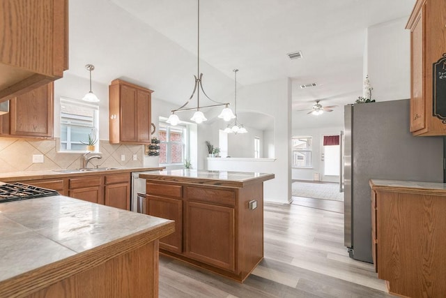 1310 Rainbow Parke Dr, Round Rock, TX 78665 - kitchen with a center island, light wood finished floors, decorative backsplash, ceiling fan, and appliances with stainless steel finishes