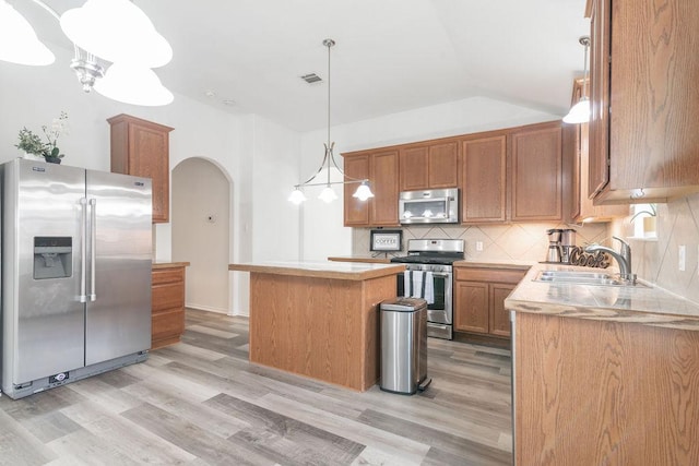 1310 Rainbow Parke Dr, Round Rock, TX 78665 - kitchen featuring appliances with stainless steel finishes, light wood-style floors, arched walkways, tasteful backsplash, and vaulted ceiling