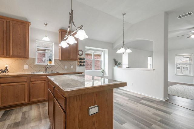 1310 Rainbow Parke Dr, Round Rock, TX 78665 - kitchen with brown cabinetry, lofted ceiling, light wood-style flooring, a kitchen island, and ceiling fan