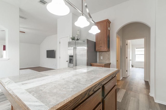 1310 Rainbow Parke Dr, Round Rock, TX 78665 - kitchen with stainless steel refrigerator with ice dispenser, arched walkways, vaulted ceiling, light wood-style floors, and light countertops