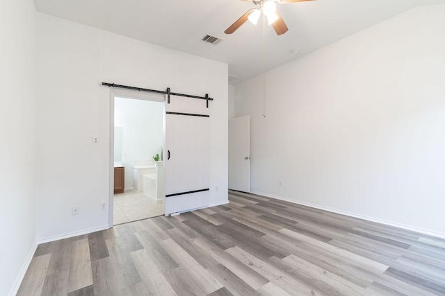 1310 Rainbow Parke Dr, Round Rock, TX 78665 - unfurnished bedroom featuring wood finished floors, a barn door, ensuite bathroom, and ceiling fan