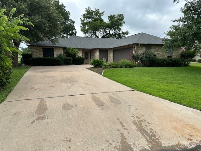 145 Turkey Run, Meadowlakes, TX 78654 - single story home with stone siding, driveway, a front yard, and an attached garage