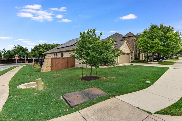 9424 Sawyer Fay Ln, Austin, TX 78748 - view of front of house featuring driveway, roof mounted solar panels, stone siding, and an attached garage