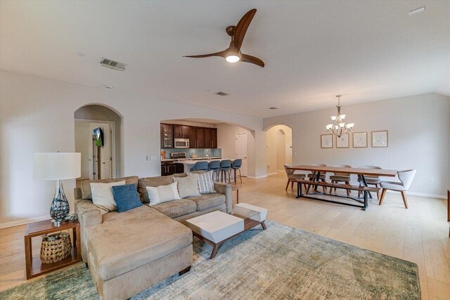 9424 Sawyer Fay Ln, Austin, TX 78748 - living area with arched walkways, light wood-style flooring, a ceiling fan, a chandelier, and baseboards