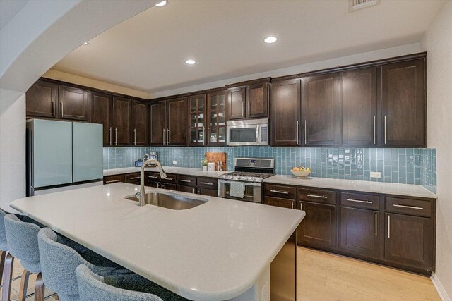 9424 Sawyer Fay Ln, Austin, TX 78748 - kitchen with appliances with stainless steel finishes, a sink, arched walkways, light wood finished floors, and dark brown cabinets