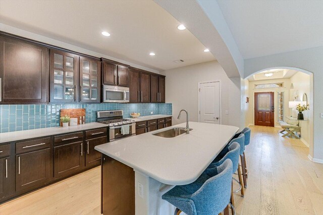 9424 Sawyer Fay Ln, Austin, TX 78748 - kitchen featuring stainless steel appliances, a sink, arched walkways, light wood-style floors, and recessed lighting