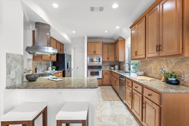 12501 Bright Sky Overlook, Austin, TX 78732 - kitchen with wall chimney range hood, appliances with stainless steel finishes, a peninsula, light stone countertops, and decorative backsplash