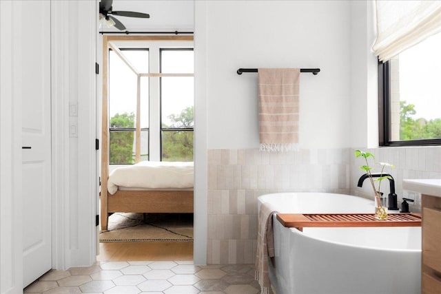 482 Running Bird Rd, Austin, TX 78737 - bathroom featuring a soaking tub, tile walls, tile patterned floors, a wainscoted wall, and ensuite bath
