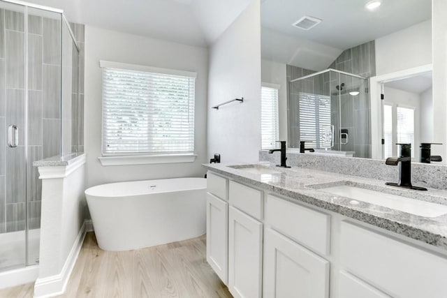 120 Periwinkle Ln, Bastrop, TX 78602 - bathroom featuring a shower stall, double vanity, a soaking tub, and wood finished floors