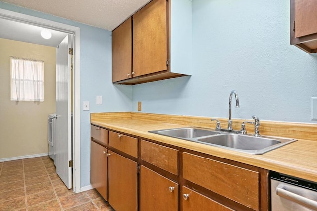 3921 Leafield Dr, Austin, TX 78749 - kitchen featuring a sink, washing machine and dryer, light countertops, stainless steel dishwasher, and baseboards