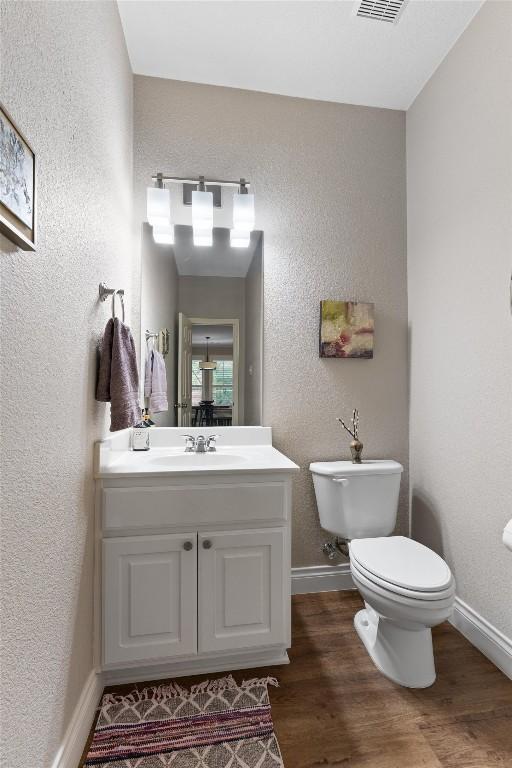 2125 Village View Loop, Pflugerville, TX 78660 - half bathroom with a textured wall, toilet, vanity, wood finished floors, and baseboards