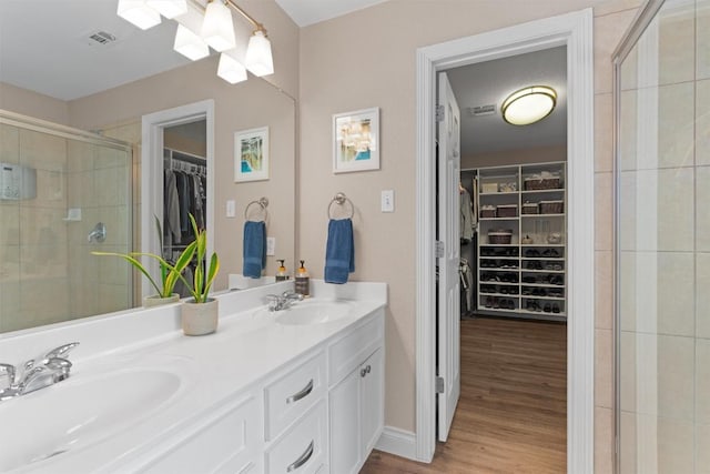 2125 Village View Loop, Pflugerville, TX 78660 - full bathroom featuring double vanity, a walk in closet, a shower stall, and wood finished floors