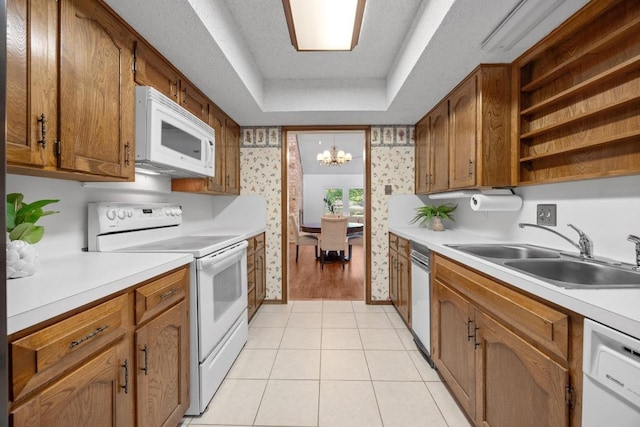 11512 Tin Cup Dr Unit 103, Austin, TX 78750 - kitchen featuring white appliances, wallpapered walls, a sink, a raised ceiling, and a chandelier