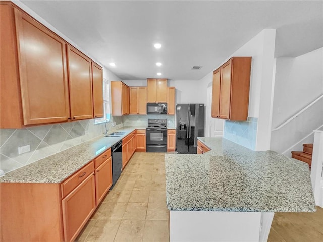 2015 Split Diamond Way, Round Rock, TX 78664 - kitchen featuring black appliances, a sink, a peninsula, light stone countertops, and decorative backsplash