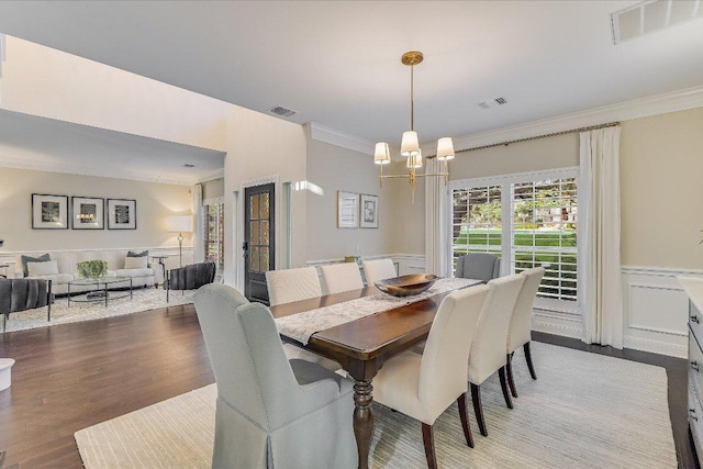 22 Wingreen Loop, The Hills, TX 78738 - dining area featuring a chandelier, crown molding, wainscoting, wood finished floors, and a decorative wall