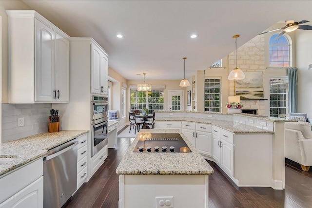 22 Wingreen Loop, The Hills, TX 78738 - kitchen with stainless steel appliances, a center island, backsplash, open floor plan, and recessed lighting