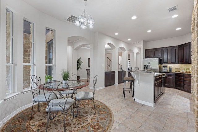 3022 Luminoso Ln E, Round Rock, TX 78681 - kitchen with a breakfast bar area, stainless steel refrigerator with ice dispenser, dark brown cabinets, arched walkways, and recessed lighting