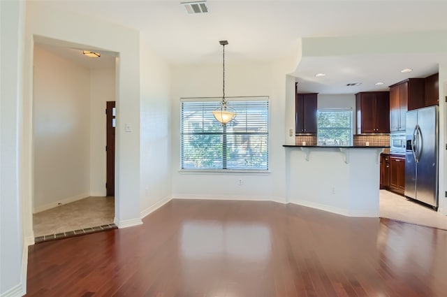 9707 Anderson Mill Rd Unit 32, Austin, TX 78750 - kitchen featuring stainless steel fridge, dark countertops, dark wood-type flooring, a breakfast bar, and tasteful backsplash