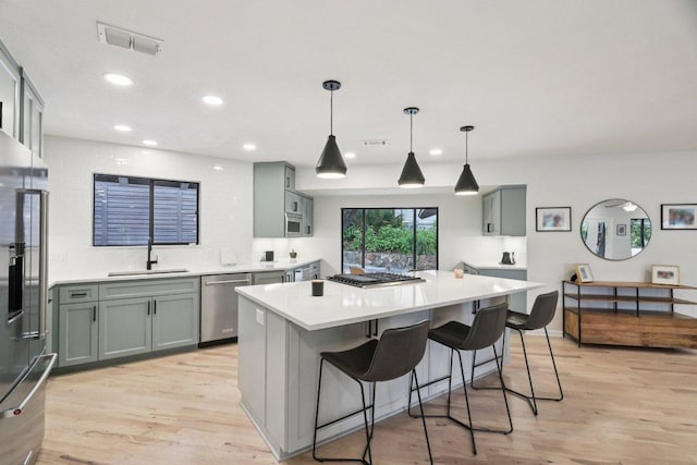 3902 Knollwood Dr Unit A, Austin, TX 78731 - kitchen with appliances with stainless steel finishes, a sink, light countertops, light wood-style flooring, and a center island